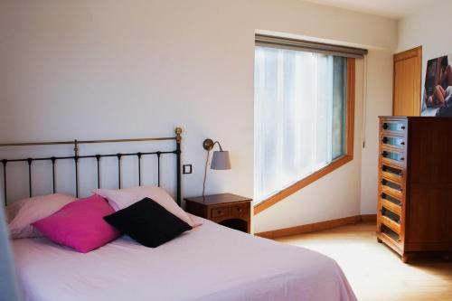 a bedroom with a bed with pink and black pillows at La Jarocha, casa con vistas al mar en Pechón in Pechón