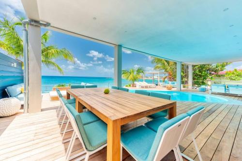 ein Esszimmer mit einem Tisch und Stühlen sowie einem Pool in der Unterkunft Surfsong Villa- Luxury Water Front Villa for 12 in Maho Reef