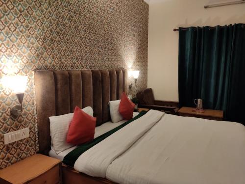 a bedroom with a large bed with red pillows at Hotel Royal in Chamba