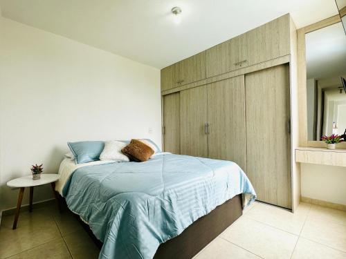 una camera da letto con un letto con lenzuola blu e uno specchio di Hermoso apartamento pereira con parking y piscina a Pereira