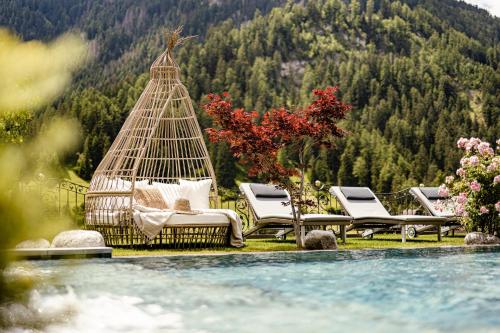a group of lounge chairs sitting next to a pool at Alpin Garden Luxury Maison & SPA - Adults Only in Ortisei
