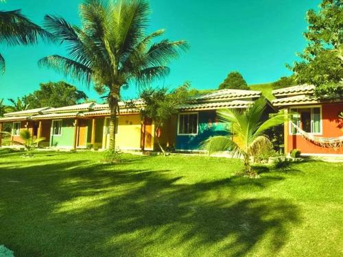 a house with palm trees in front of a yard at Pousada Sítio da Floresta in Sana