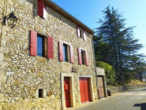 ein Steingebäude mit roten Rollläden auf einer Straße in der Unterkunft Grande Maison Luberon Ventoux in Aurel