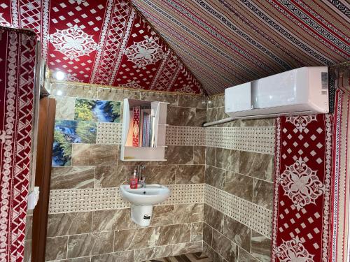 a bathroom with a sink and red and white tiles at Wadi Rum Khalid luxury camp in Wadi Rum