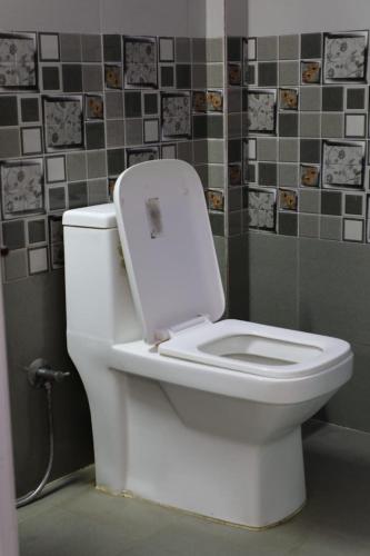 a white toilet with the lid up in a bathroom at Ammukutty's Cottage in Munnar