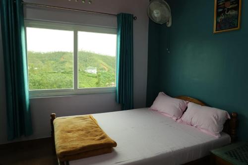 a small bedroom with a bed with a window at Ammukutty's Cottage in Munnar