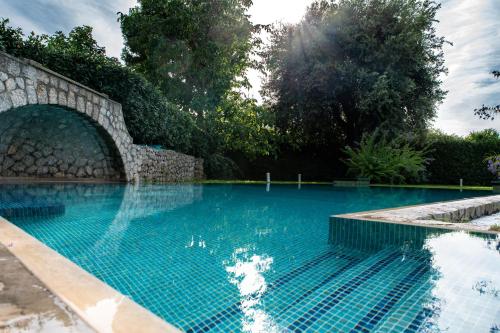 a swimming pool with a stone wall and blue water at Capri Villa Vittoria by Capri Property in Anacapri