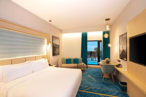 a hotel room with a bed and a desk and a television at Maani Muscat Hotel & Suites in Muscat
