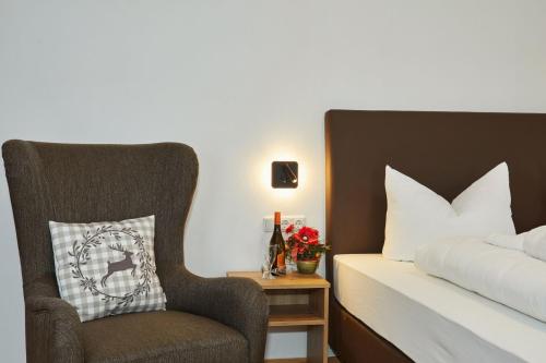 a bedroom with a bed and a chair with a pillow at Das Salzburgblick in Ainring