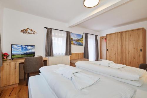 two beds in a room with a desk and a television at Das Salzburgblick in Ainring