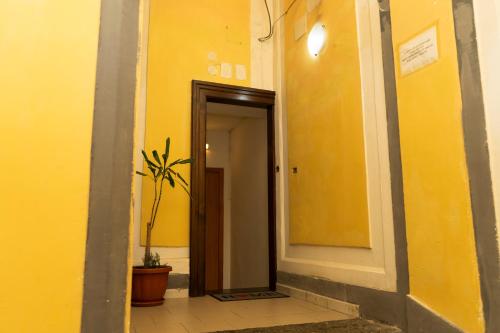 un pasillo con una pared amarilla y una planta en Donna Chiara Holiday House - Toledo, en Nápoles