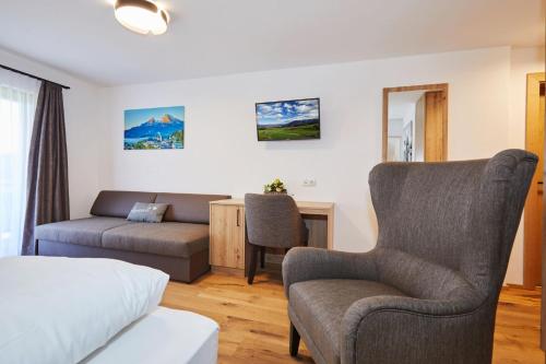 a bedroom with a bed and a couch and a chair at Das Salzburgblick in Ainring