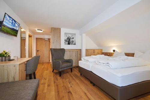 um quarto de hotel com uma cama, uma secretária e cadeiras em Das Salzburgblick em Ainring