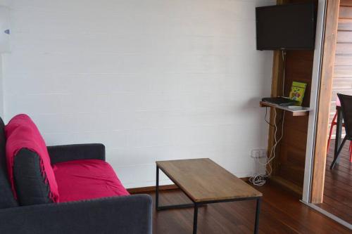 a living room with a red couch and a table at Bungalow Belvu 2chb - piscine personnelle in Le Marin