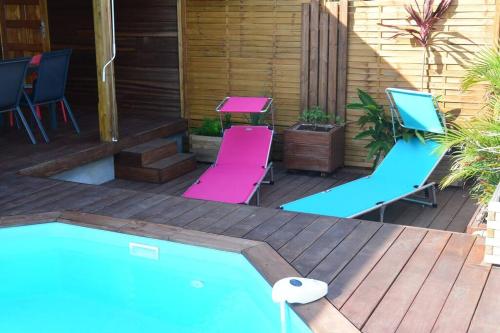 a deck with two chairs and a swimming pool at Bungalow Belvu 2chb - piscine personnelle in Le Marin