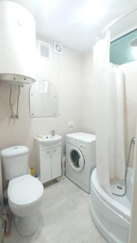 een witte badkamer met een toilet en een wasmachine bij 2-комнатная квартира Ген.Дбар/Лакоба in Sukhumi