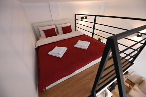 a small bedroom with a bed with red sheets and towels at BEL GALLERIES ( Karadjordjeva street ) in Sajmište