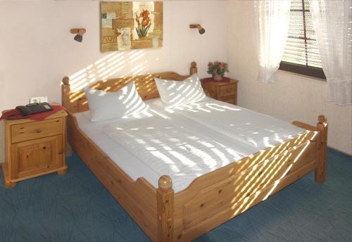 a bedroom with a large wooden bed with white sheets at Hotel-Restaurant-Pfaelzer-Stuben in Bruchmühlbach-Miesau