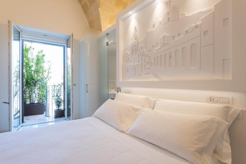 ein weißes Schlafzimmer mit einem großen Bett mit weißen Kissen in der Unterkunft Vittorio Veneto Matera Luxury Rooms in Matera
