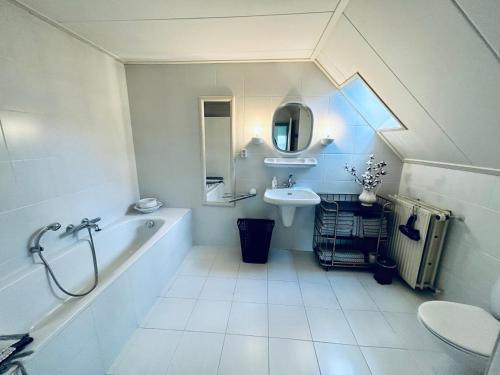 Baño blanco con bañera y lavamanos en Hofstede Dongen Vaart, en Dongen