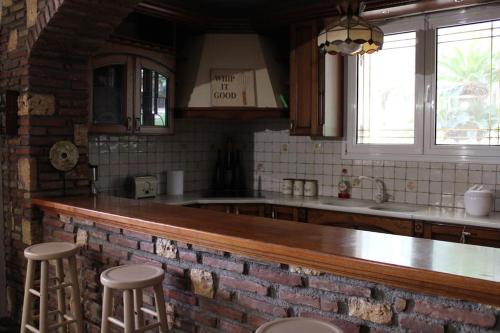a kitchen with a brick wall and a counter with stools at Άνεση και ήρεμία in Oropós
