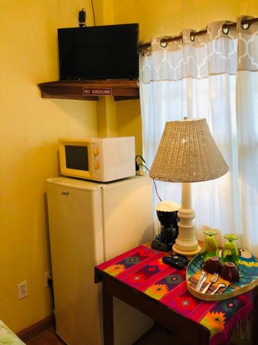 a table with a lamp and a microwave on top of a refrigerator at Coral Cove Inn in Maya Beach