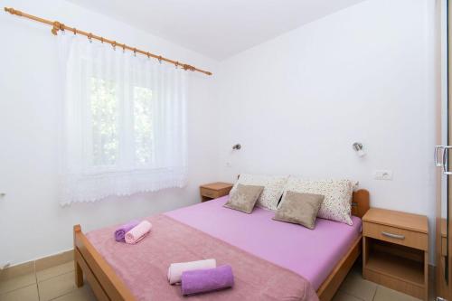 - une chambre avec un lit doté de draps violets et une fenêtre dans l'établissement Apartments Igor, à Jakišnica