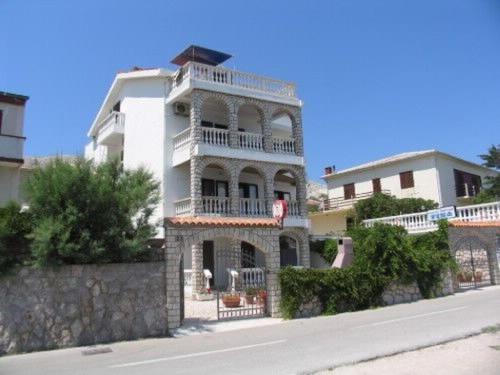 a white building with a balcony on the side of a street at Apartments Tina in Pag