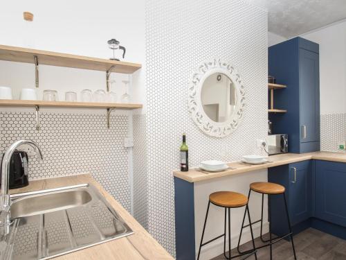 a kitchen with blue cabinets and a sink and two stools at Oystercatcher Bay in Weymouth