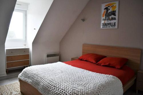 a bedroom with a bed with a red and white comforter at Cœur des chevaux in Deauville