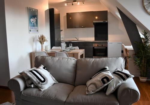 a living room with a couch and a kitchen at Cœur des chevaux in Deauville