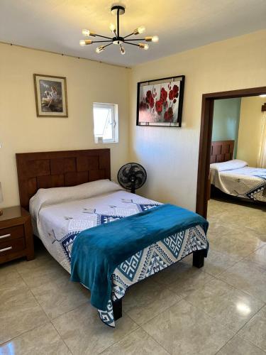 a bedroom with a bed with a blue blanket on it at Departamento en Tequila María Concepción in Tequila