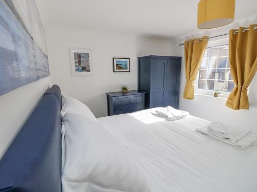1 dormitorio con 1 cama blanca y armario azul en Tennyson View, en Totland