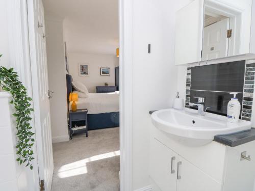 a white bathroom with a sink and a bedroom at Tennyson View in Totland