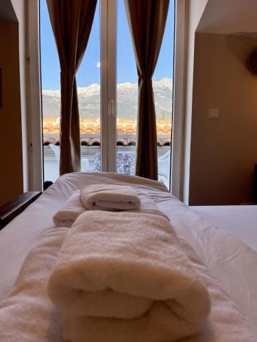 a pile of towels on a bed in front of a window at Villa Merci Budva in Budva