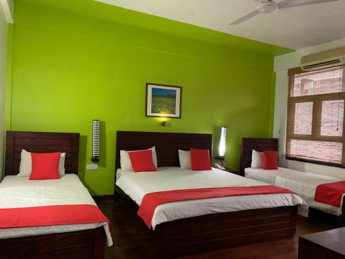 2 camas en una habitación verde con paredes verdes en Subhas Tourist Hotel en Jaffna