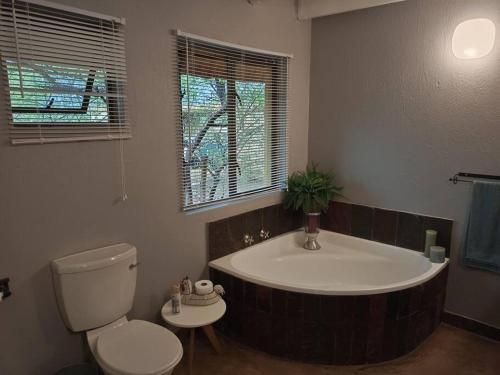 a bathroom with a bath tub and a toilet at Hoedspruit Bush Cottage in Hoedspruit