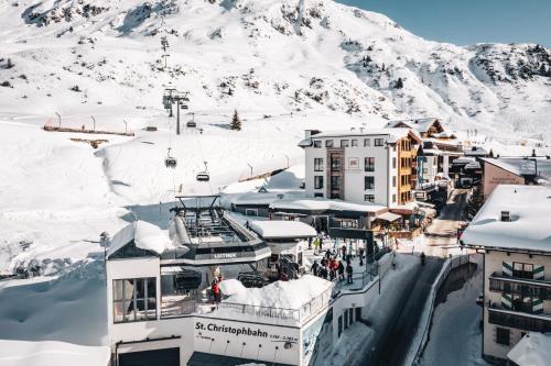 a town covered in snow with a mountain in the background at Hotel Maiensee in Sankt Christoph am Arlberg