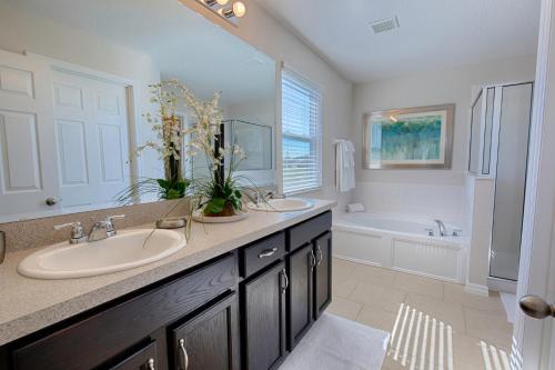 uma casa de banho com 2 lavatórios, uma banheira e um lavatório. em 10 Guest Villa in Tranquil Setting Near Disney Pool & Spa by Orlando Holiday Rental Homes 1153 em Davenport
