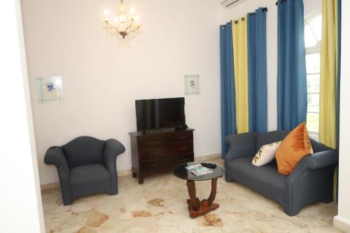 a living room with two chairs and a tv at Jamaica Palace Hotel in Port Antonio