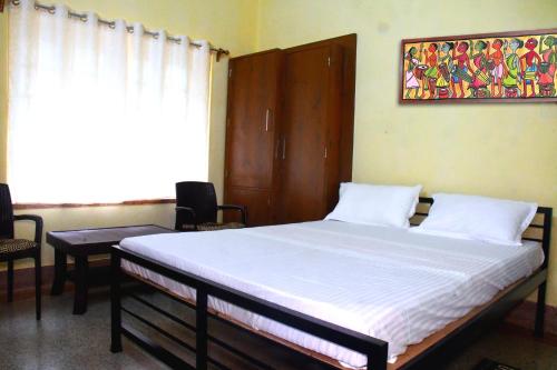 - une chambre avec un lit, deux chaises et une fenêtre dans l'établissement Jhargram Eshani Hotels and Guest House, à Jhārgrām
