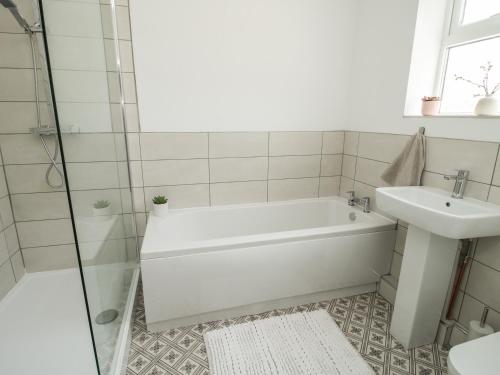 a white bathroom with a tub and a sink at Bethania in Oswestry