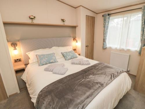 a bedroom with a large white bed with blue pillows at 20 Wolds View in Ganton
