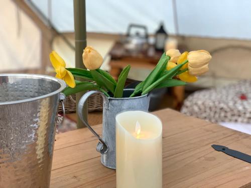 a candle and a vase with flowers on a table at Home Farm Radnage Glamping Bell Tent 5, with Log Burner and Fire Pit in High Wycombe
