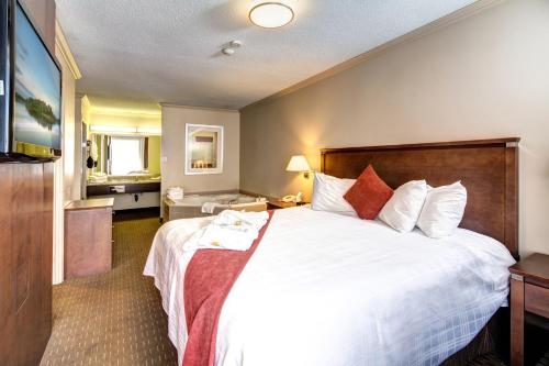 a hotel room with a large bed with white sheets and red pillows at Best Western Plus Guildwood Inn in Sarnia