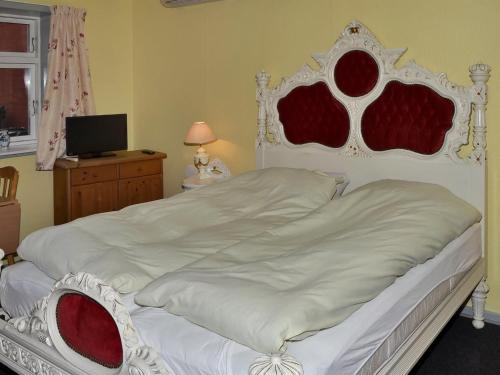 a bedroom with a white bed with a red and white headboard at Apartment Gunhild - 22km from the sea in Western Jutland by Interhome in Bredebro