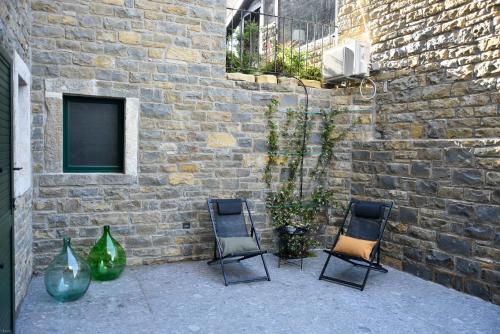 three chairs and vases sitting next to a brick wall at L'Abbraccio della Quercia - Suites in Buje