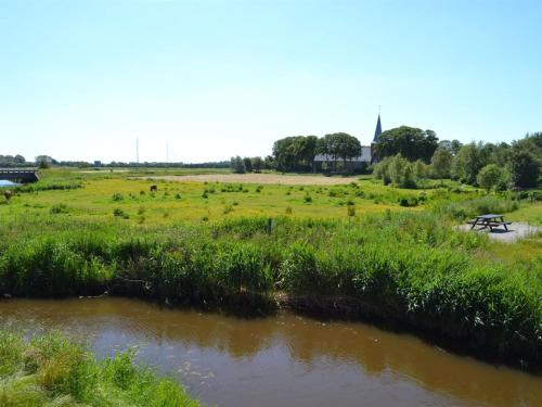 a field with cows grazing in the grass next to a river at Apartment Hendricke - 22km from the sea in Western Jutland by Interhome in Bredebro