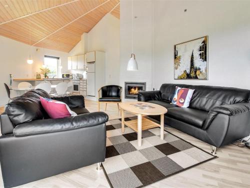 a living room with black leather couches and a table at Holiday Home Jani - 25km from the sea in Western Jutland by Interhome in Toftlund