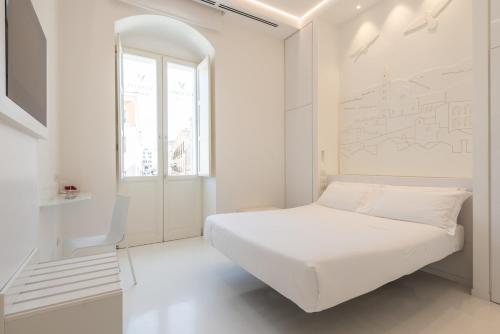 a white bedroom with a bed and a window at Vittorio Veneto Matera Luxury Rooms in Matera